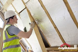 Builder Fitting Insulation Into Roof Of New Home